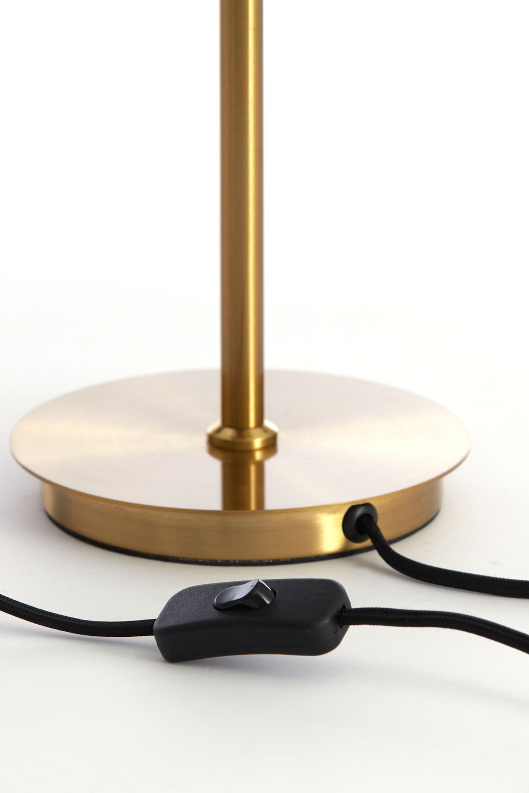 Nahaufnahme der Basis einer Tischleuchte MEDINA in goldener Farbe mit einem schwarzen Kabel und Schalter.