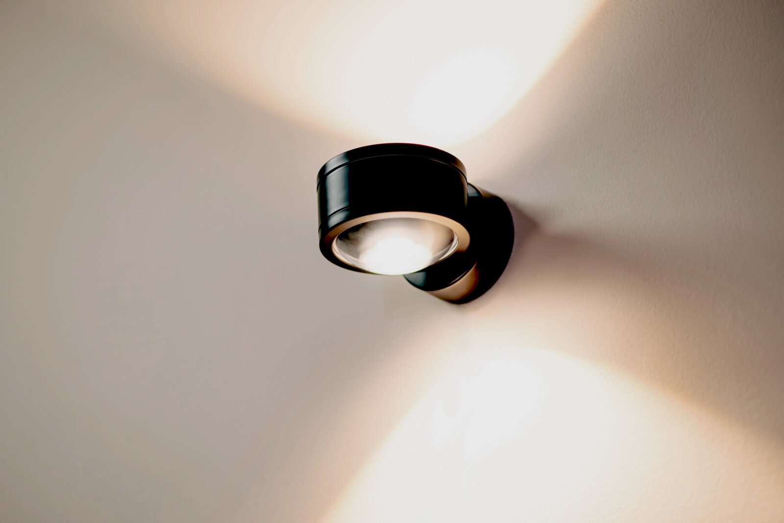 Moderne LED Wandleuchte in schwarzem Gehäuse, an der Wand montiert, mit nach oben und unten gerichteten Lichtstrahlen, seitliche Perspektive