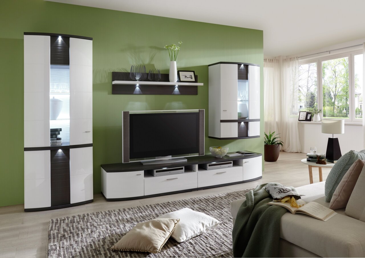 Zurbrüggen Wandpaneel CABANA Modernes Wohnzimmer mit grün gestrichener Wand, ausgestattet mit einem eleganten Wandpaneel, das über einem Fernseher montiert ist. Perspektive von der Seite, die den gesamten Raum zeigt.