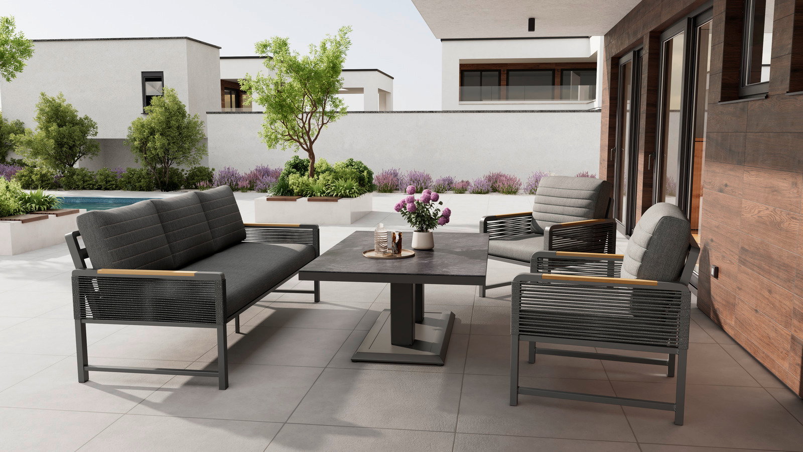 Moderne Loungegarnitur auf einer Terrasse mit Blick auf einen Garten, bestehend aus einem Tisch, einem Sofa und Sesseln in stilvollem Design.