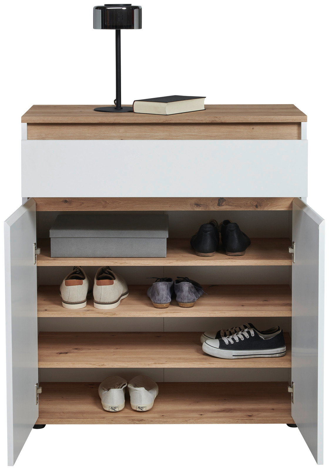 Kommode mit weißer Front und Holzoberfläche, offene Türen zeigen mehrere Regalböden mit Schuhen und einer Box, darauf eine Lampe und ein Buch, frontale Perspektive
