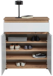 Kommode mit weißer Front und Holzoberfläche, offene Türen zeigen mehrere Regalböden mit Schuhen und einer Box, darauf eine Lampe und ein Buch, frontale Perspektive