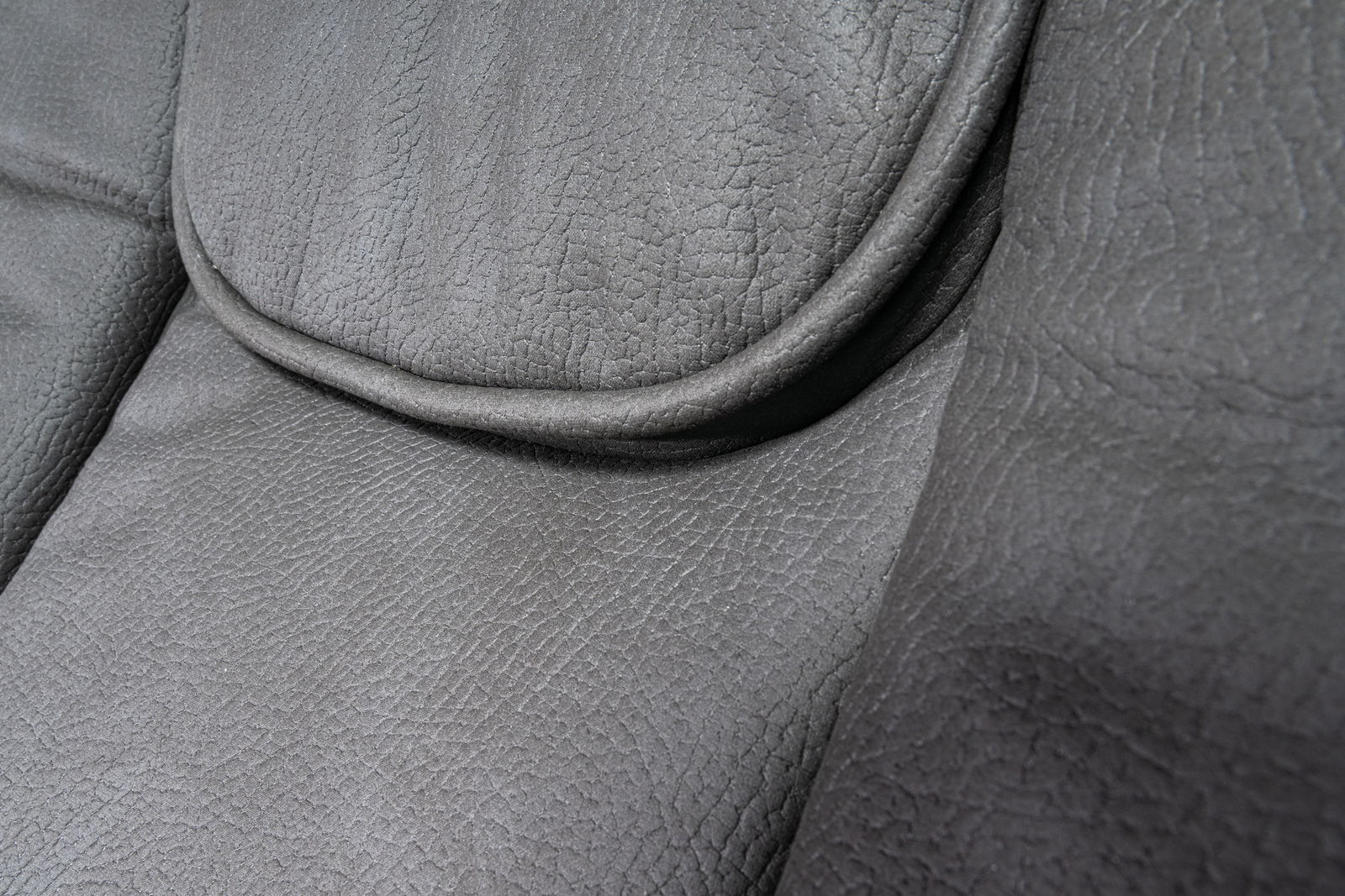 Nahaufnahme der grauen Lederpolsterung eines Chefsessels, Detailansicht der Sitzfläche
