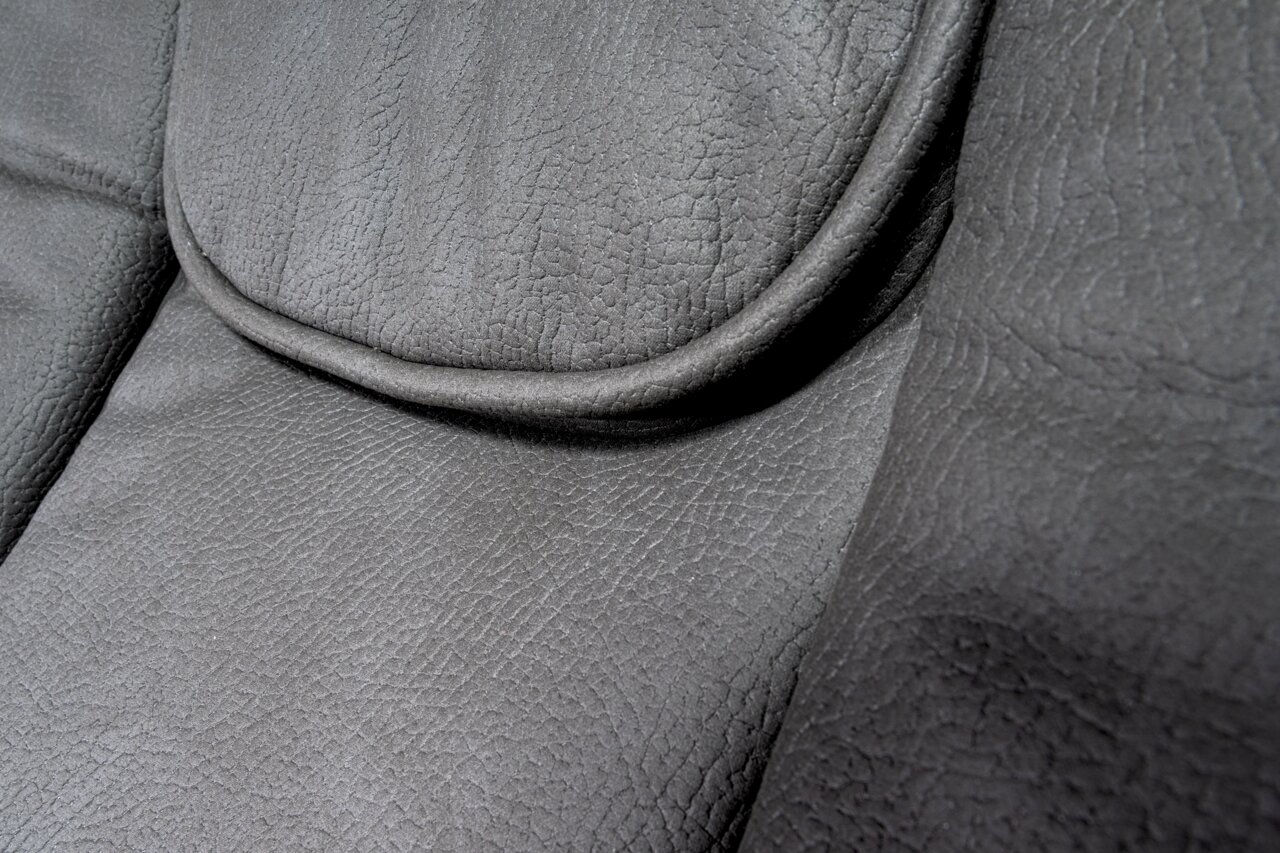 Close-up van de grijze lederen bekleding van een directiestoel, detailfoto van de zitting