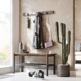 Wandgarderobe mit Haken, an der ein Mantel und eine Tasche hängen, daneben ein Kaktus in einem Topf, im Vordergrund eine Bank mit Kopfhörern und einer Trinkflasche, Perspektive von schräg vorne