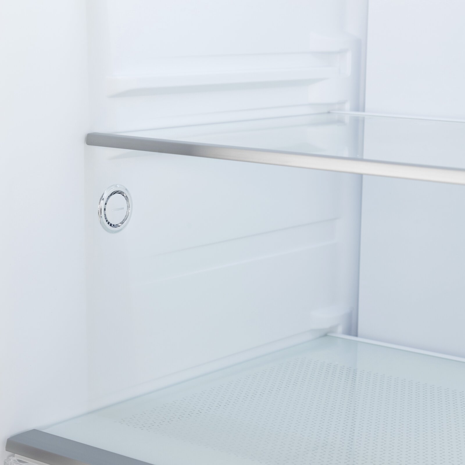 Interieur van een koelkast met glazen legplank en ventilatieopening, gezien van voren in close-up