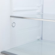 Interieur van een koelkast met glazen legplank en ventilatieopening, gezien van voren in close-up
