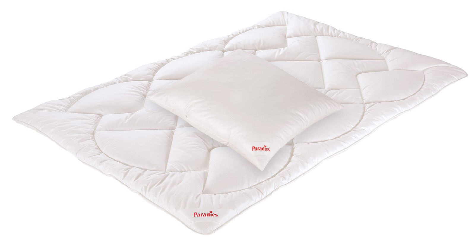 Bettenset bestehend aus einer weißen Decke und einem Kissen, beide mit dem Logo 'Paradies', aus der Vogelperspektive fotografiert.