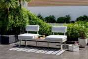 Moderne Lounge-Kombination mit grauen Kissen und Tisch in einem Garten, seitliche Perspektive