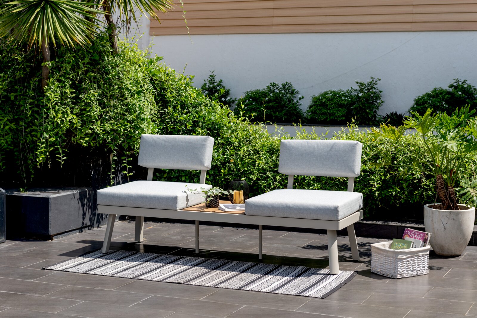 Moderne Lounge-Kombination mit grauen Kissen und Tisch in einem Garten, seitliche Perspektive