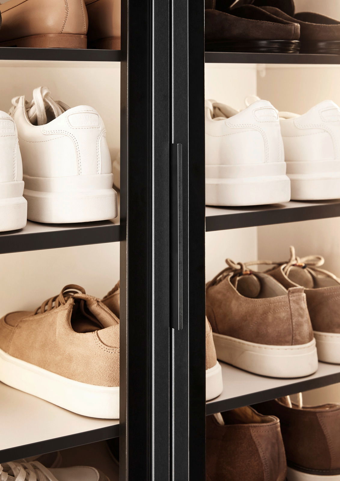 Nahaufnahme eines XL-Schuhschrankes mit Glastüren, gefüllt mit verschiedenen Schuhen in Weiß- und Brauntönen, von der Seite betrachtet.