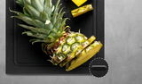 Schwarzes Schneidebrett mit geschnittener Ananas, Draufsicht