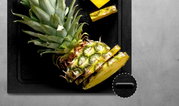 Schwarzes Schneidebrett mit geschnittener Ananas, Draufsicht