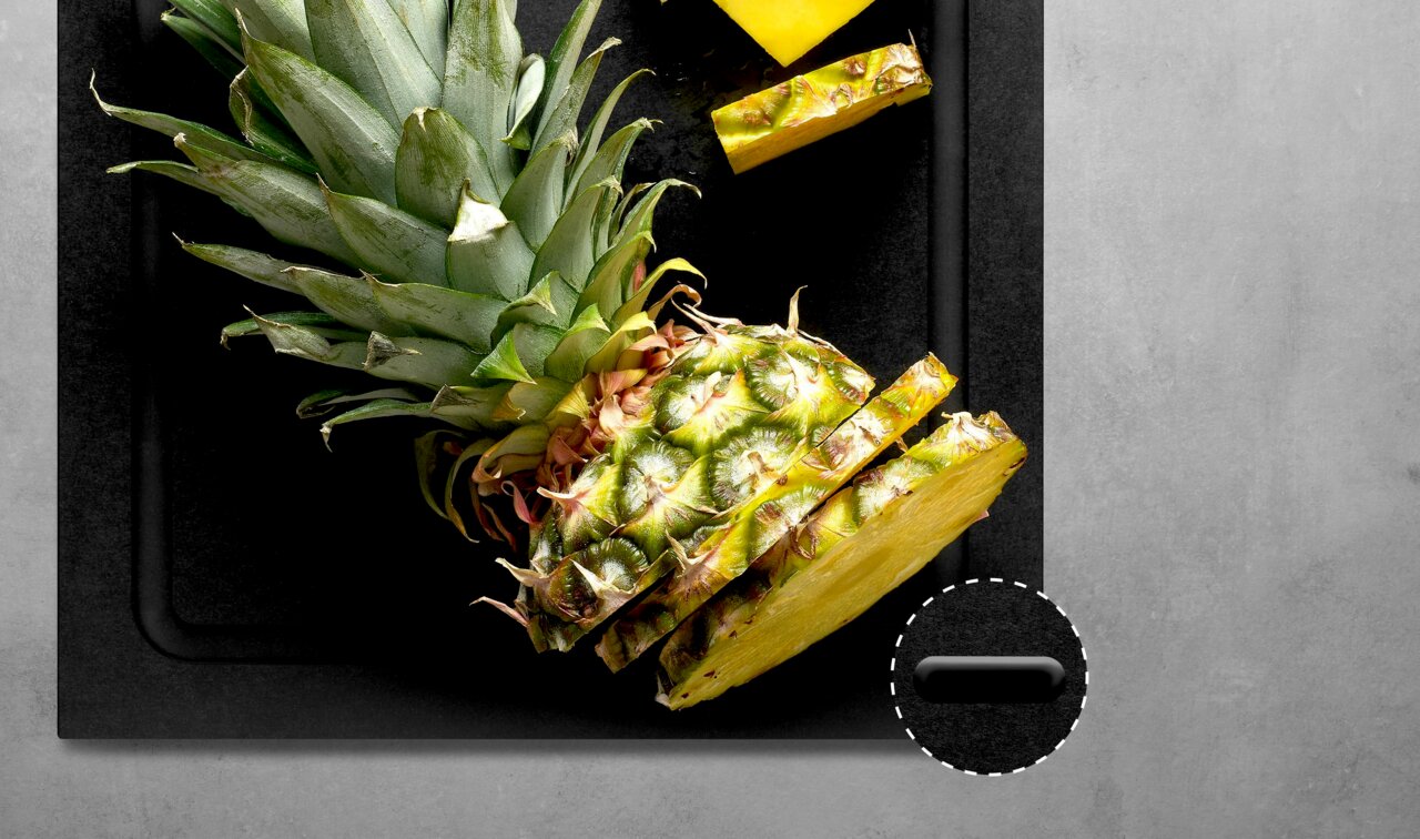 Schwarzes Schneidebrett mit geschnittener Ananas, Draufsicht
