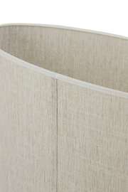 Nahaufnahme eines zylindrischen Lampenschirms aus beigefarbenem, grob gewebtem Stoff mit sichtbarer Naht, leicht von oben schräg fotografiert.