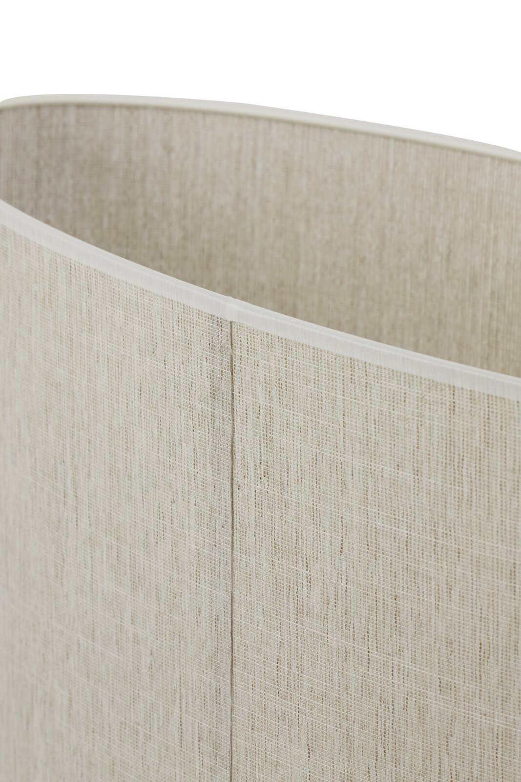 Close-up van een cilindervormige lampenkap van beige, grof geweven stof met zichtbare naad, licht schuin van bovenaf gefotografeerd.