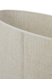 Close-up van een cilindervormige lampenkap van beige, grof geweven stof met zichtbare naad, licht schuin van bovenaf gefotografeerd.
