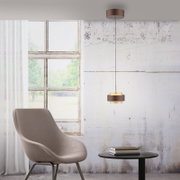 Moderne LED-Hängeleuchte in einem stilvollen Raum mit einem Sessel und einem Tisch, seitliche Perspektive