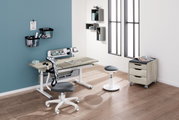 Moderner Schreibtisch mit ergonomischem Stuhl und Hocker in einem stilvollen, hellen Raum mit Holzboden, aus der Perspektive von vorne links betrachtet.