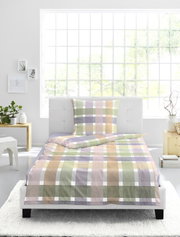Vooraanzicht van een eenpersoonsbed met geruit beddengoed in zachte pastelkleuren zoals groen, roze, lila en beige, stijlvol gepresenteerd in een lichte slaapkamer.