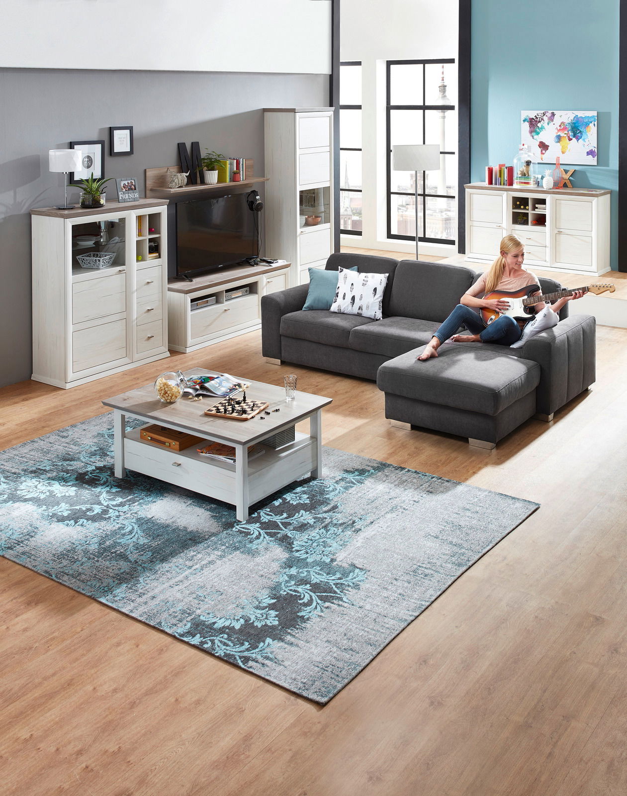 Wohnzimmer mit grauem Ecksofa, Couchtisch und Wohnwand in heller Holzoptik, seitliche Perspektive