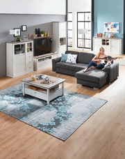 Wohnzimmer mit grauem Ecksofa, Couchtisch und Wohnwand in heller Holzoptik, seitliche Perspektive