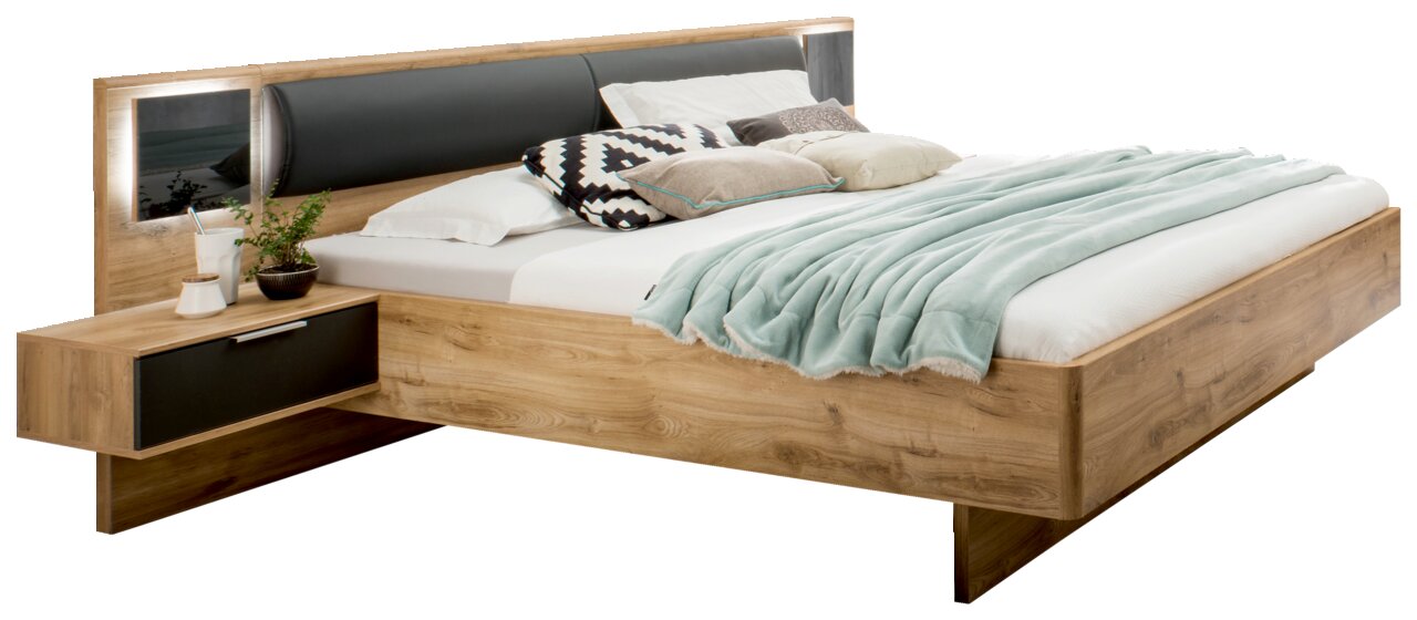 Holzbett mit integriertem Nachttisch, Kopfteil mit schwarzem Polster und dekorativen Kissen, seitliche Perspektive