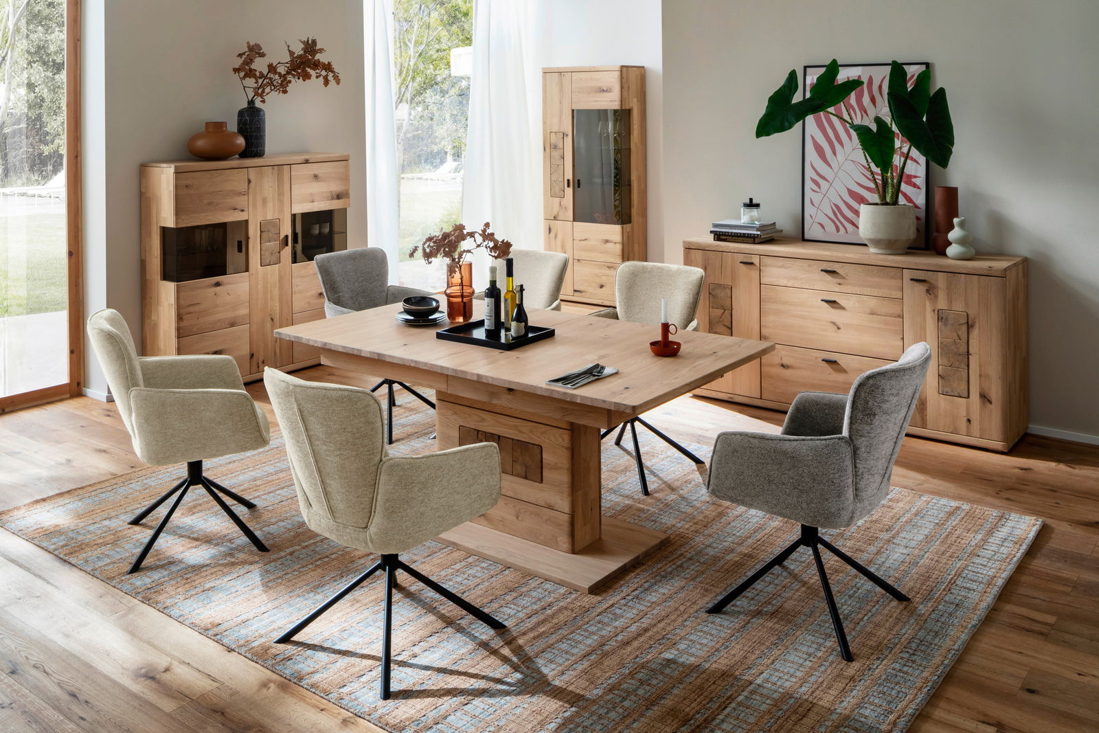 Esszimmer mit Holztisch und Stühlen, umgeben von Vitrinen und Sideboard aus Holz, aus der Perspektive des Raumes betrachtet.