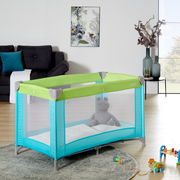 Reisebett in einem modernen Wohnzimmer, seitliche Perspektive, mit grünem und türkisfarbenem Design, gefüllt mit einem Plüschtier.