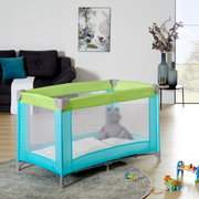 Reisebett in einem modernen Wohnzimmer, seitliche Perspektive, mit grünem und türkisfarbenem Design, gefüllt mit einem Plüschtier.