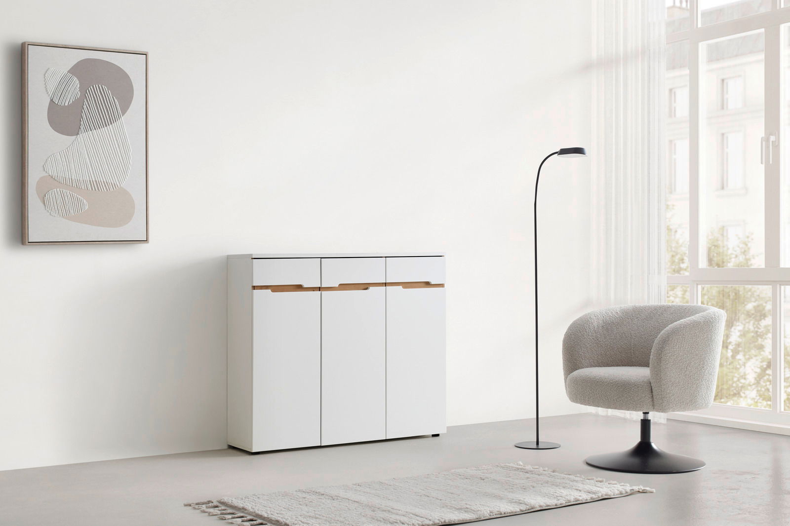 XORA Kommode MEMPHIS Moderne weiße Kommode mit Holzgriffen, frontal fotografiert, in einem minimalistisch eingerichteten Raum mit einem Sessel, Stehlampe und abstraktem Wandbild.