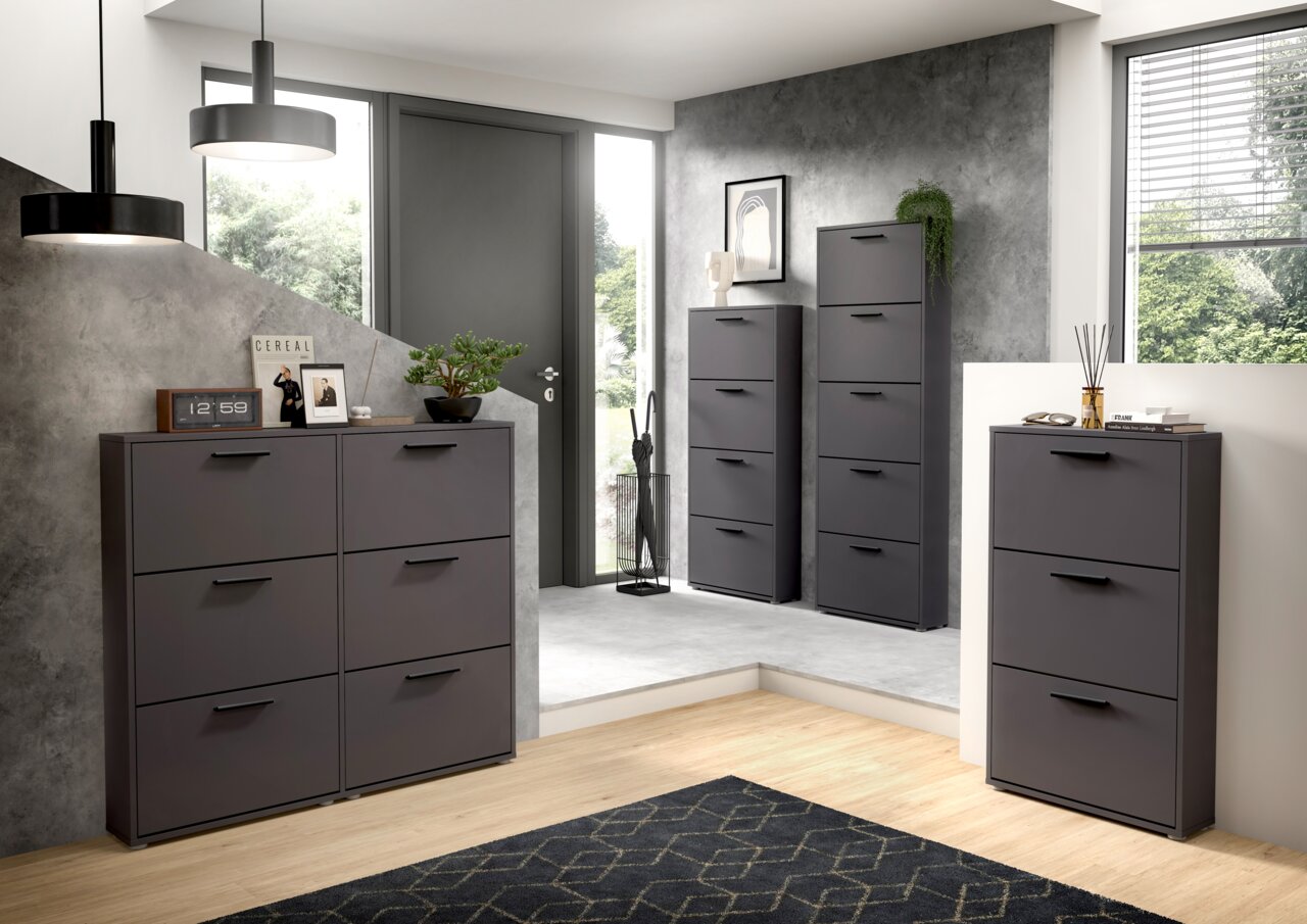 Moderner Schuhkipper in Anthrazit mit sechs Fächern, in einem stilvollen Eingangsbereich mit grauer Wand und Holzboden, aus der Perspektive von vorne links betrachtet.