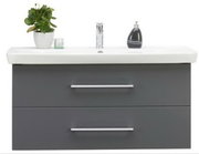 Moderne wastafel met twee lades in grijze kleur, met daarop een plant en een zeepdispenser, gezien van voren.