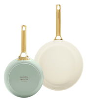 Zwei Bratpfannen in einem Set, eine mit hellgrüner Unterseite und die andere in Cremefarbe, beide mit goldfarbenen Griffen, aus der Vogelperspektive.