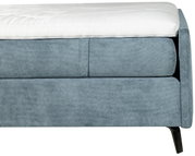 Nahaufnahme eines blauen Boxspringbetts mit weißem Topper, seitliche Perspektive