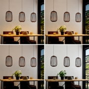 Drei moderne Hängeleuchten mit zylindrischem Drahtschirm in Schwarz/Kupfer hängen über einem Holztisch im Essbereich, frontale Perspektive auf die Leuchten und den Tisch.