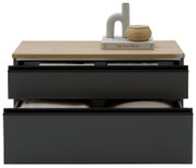 Modernes Sideboard mit zwei schwarzen Schubladen und heller Holzplatte, dekoriert mit Buch, Keramikvase und geflochtenem Korb, frontal in leicht erhöhter Perspektive