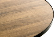 Detailaufnahme einer runden Tischplatte in Holzoptik mit schwarzem Rand, leicht von oben fotografiert
