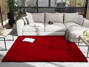 Roter Fellteppich in einem modernen Wohnzimmer mit beiger Couch, aus der Vogelperspektive betrachtet.