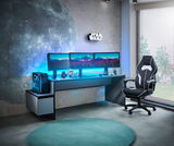 Gaming-Setup mit beleuchtetem Tisch, drei Monitoren, Towerunit und Gaming-Stuhl aus seitlicher Perspektive