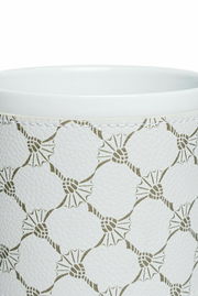 Nahaufnahme eines weißen Porzellanbechers mit grünem geometrischem Muster und genähter Textur.