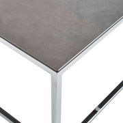 Moderner Couchtisch mit dunkler Tischplatte und glänzendem Metallgestell, Perspektive von oben.