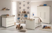 Kinderzimmer mit Wandboard, Wickelkommode, Regal und Kinderbett in moderner, heller Einrichtung, seitliche Perspektive