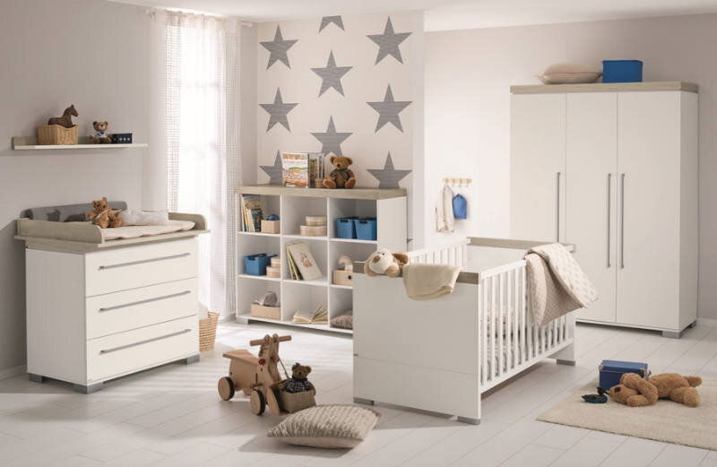 Kinderzimmer mit Wandboard, Wickelkommode, Regal und Kinderbett in moderner, heller Einrichtung, seitliche Perspektive