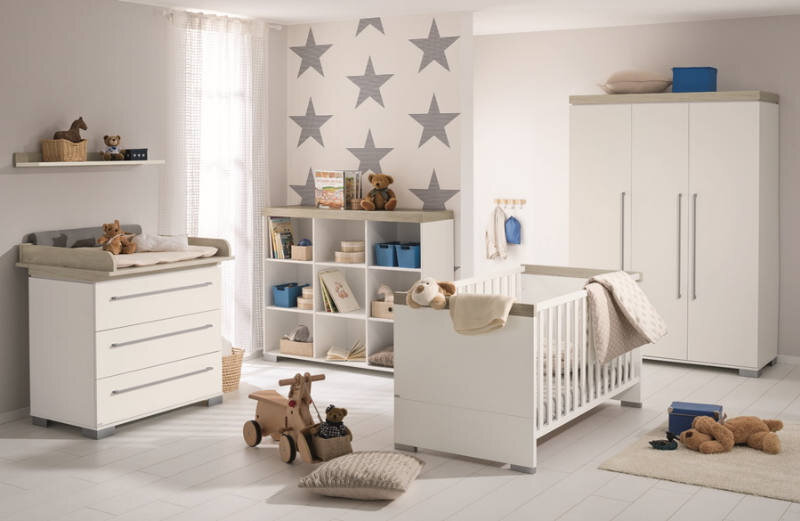 Kinderzimmer mit Wandboard, Wickelkommode, Regal und Kinderbett in moderner, heller Einrichtung, seitliche Perspektive