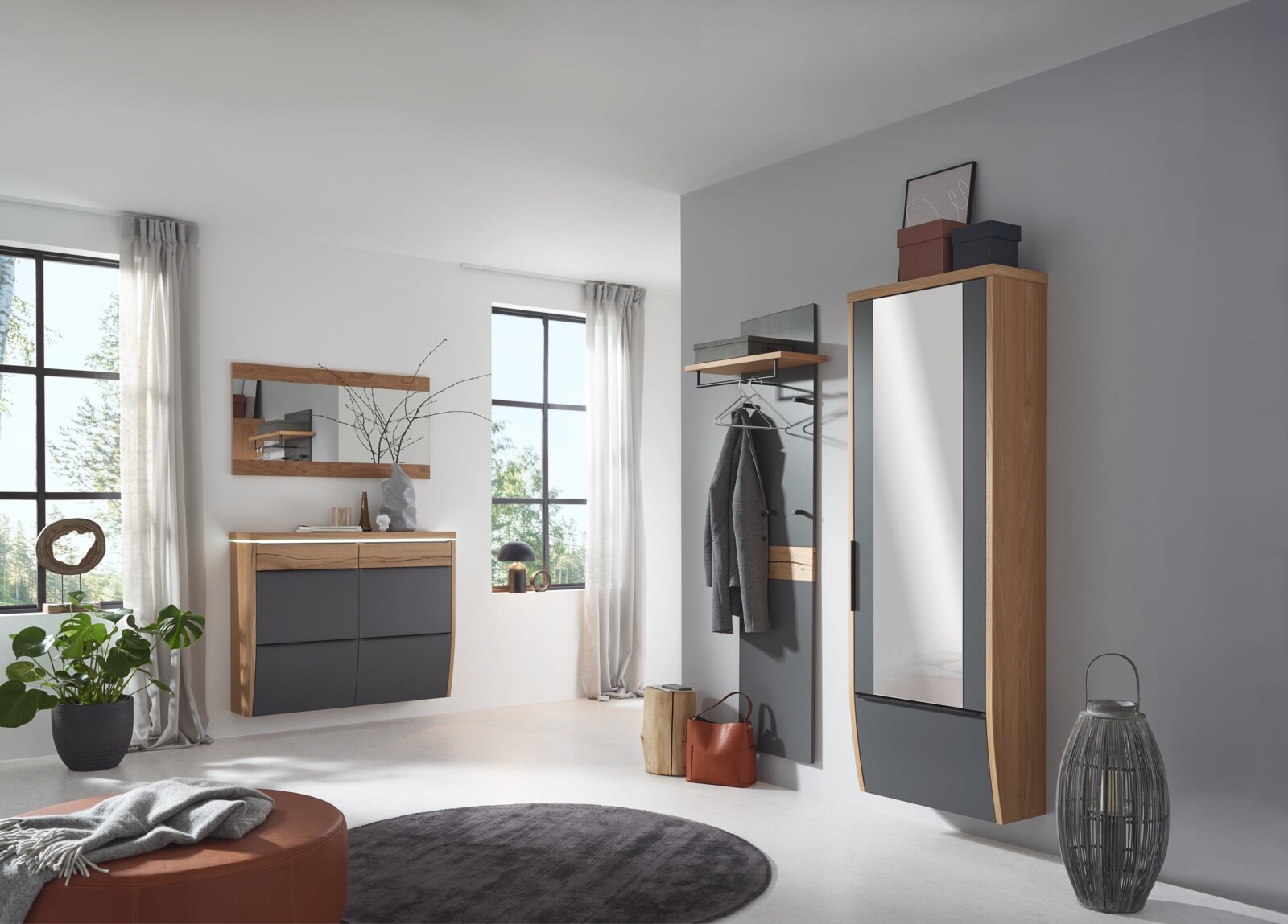 Modernes Garderoben-Set im Flur mit Hängeschrank mit Spiegel, Wandgarderobe und Kommode in Eiche-Optik und Anthrazit, fotografiert aus schräger Frontperspektive im hellen Raum.