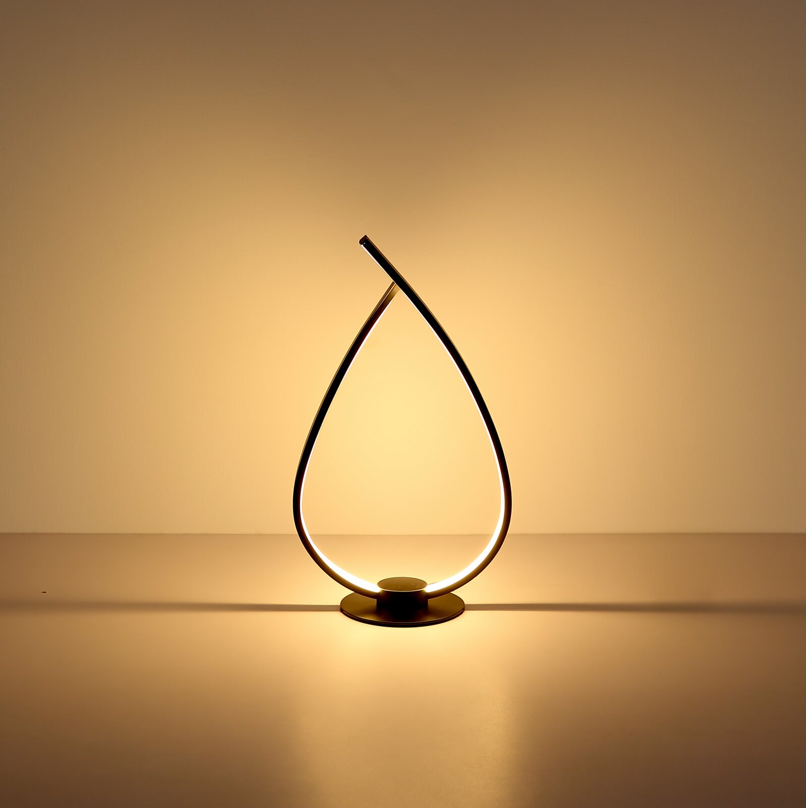 Moderne LED-Tischlampe in tropfenförmigem, gebogenem Design mit warmweißem Licht auf rundem Sockel, frontal aus Augenhöhe fotografiert