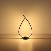 Moderne LED-Tischlampe in tropfenförmigem, gebogenem Design mit warmweißem Licht auf rundem Sockel, frontal aus Augenhöhe fotografiert