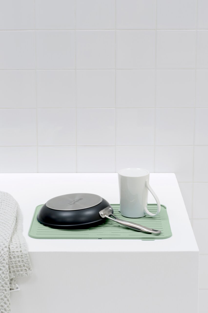 Silikon Abtropfmatte in mintgrün mit einer Pfanne und einer Tasse darauf, seitliche Perspektive
