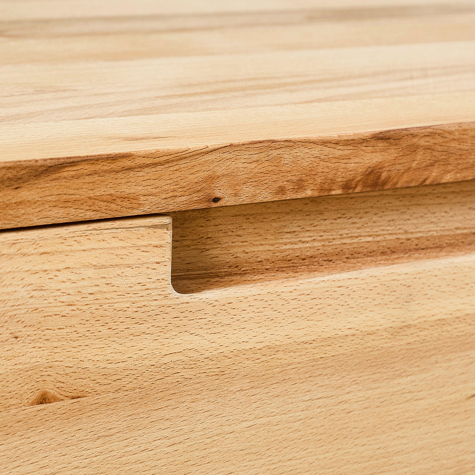 Nahaufnahme eines Hängeschuhschranks aus Holz mit natürlicher Maserung und Griffmulde.
